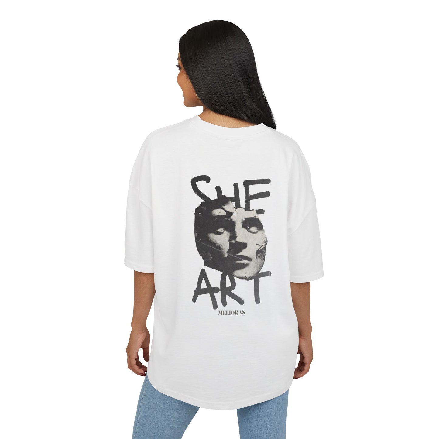 Frau trägt das weiße Oversized-T-Shirt ‚She Art‘ von Melioras. Urbaner Look mit schwarz-weißem Gesichtskunstwerk. Weicher Baumwollstoff, entspannter Schnitt.