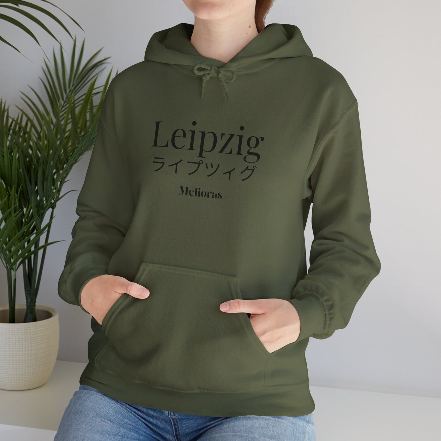 Junge Frau trägt einen olive grünen Oversized Hoodie mit Leipzig Print.