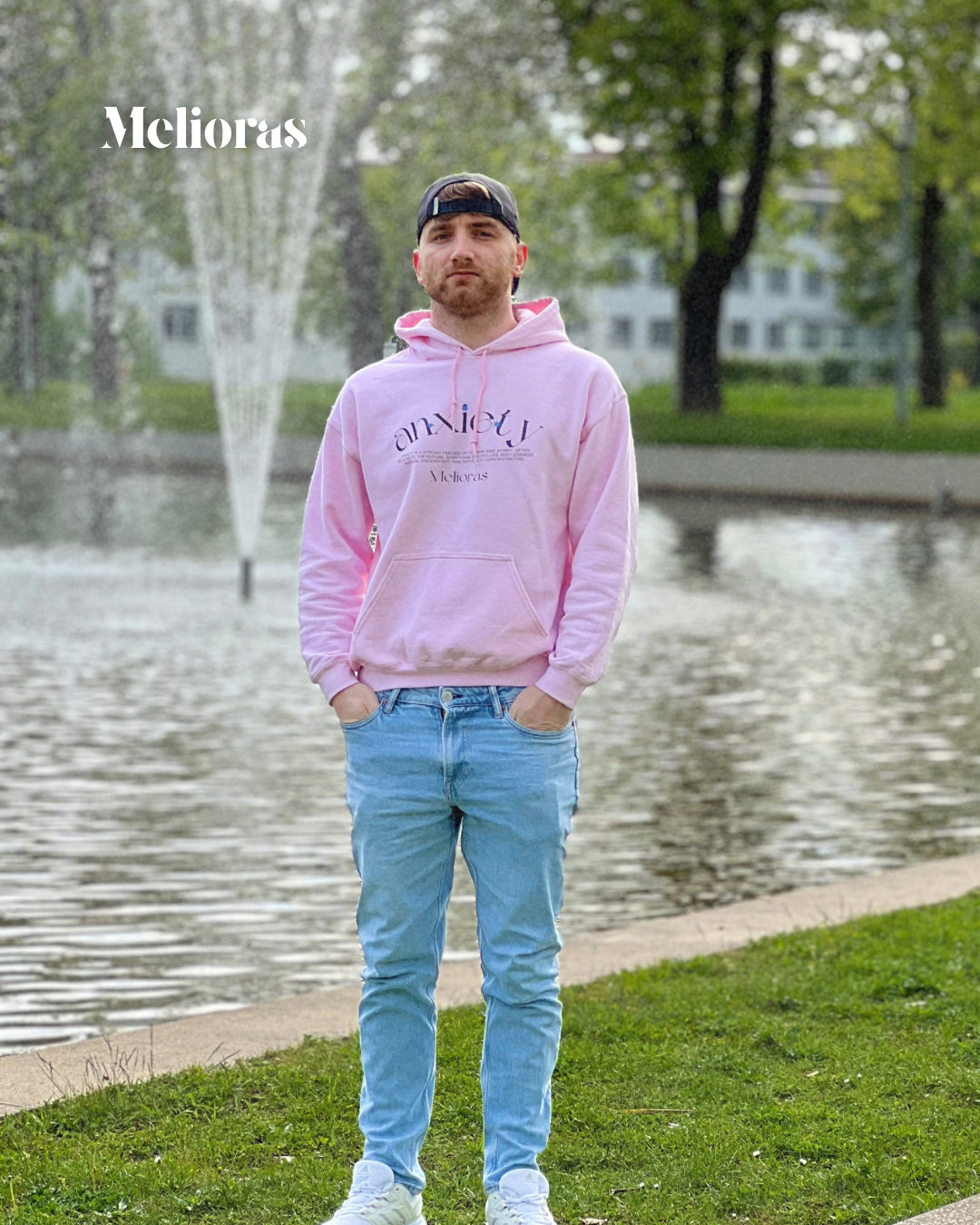Gründer von Melioras trägt den pinken Anxiety Awareness Hoodie vor dem Brunnen in Leipzig. Unisex Streetwear-Statement für mentale Gesundheit.