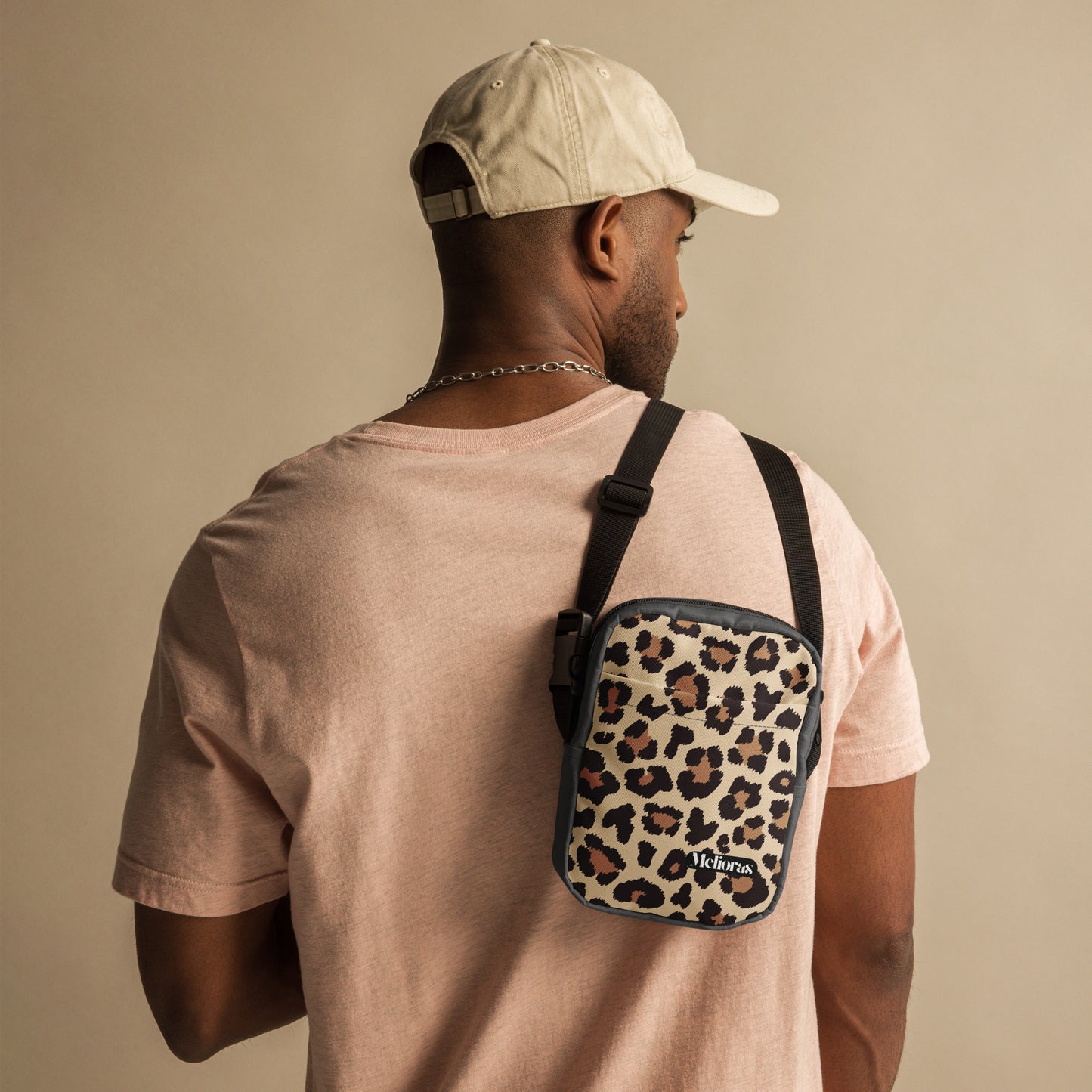 Mann trägt Umhängetasche mit Leo Print und Melioras Logo lässig über der Schulter – Streetwear Look für Herren